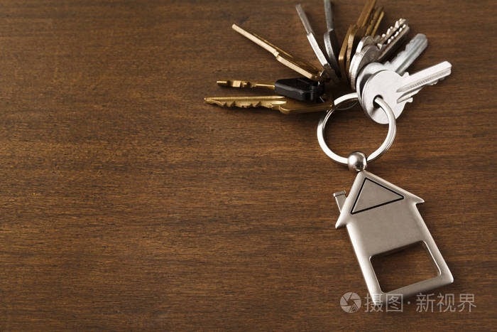 一串钥匙与房子形状的钥匙扣在白色木头