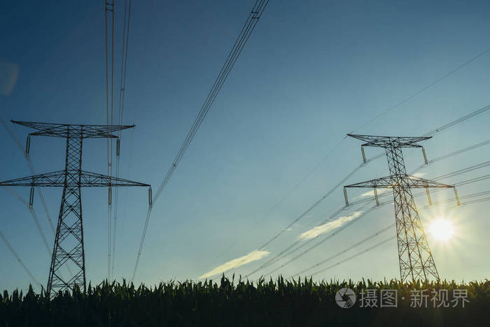 法国诺曼底的蓝天上有阳光的高压电线和输电塔。乡村景观。发电和配电。电力工业与自然