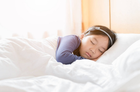 可爱的亚洲女孩睡在白色的毯子