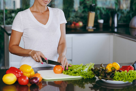 一个年轻的女人用小刀在厨房里切蔬菜。健康食品蔬菜沙拉。节食概念。健康的生活方式。在家做饭。准备食物