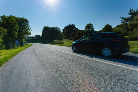 在法国诺曼底的一个阳光明媚的日子里, 汽车在柏油路上行驶, 穿过绿色