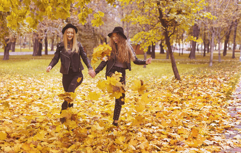 两个戴着帽子的快乐女孩在秋天公园散步
