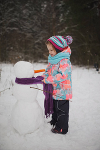 女孩做雪人在冬天公园
