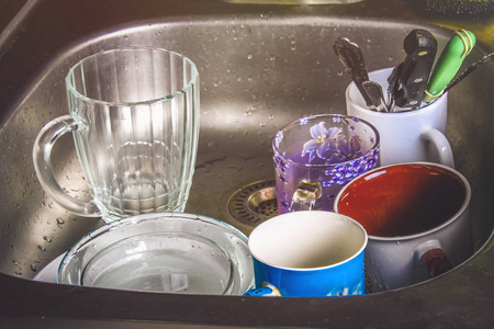 脏盘子里的泡沫在水槽里等待洗涤。杯子, 盘子, 餐具