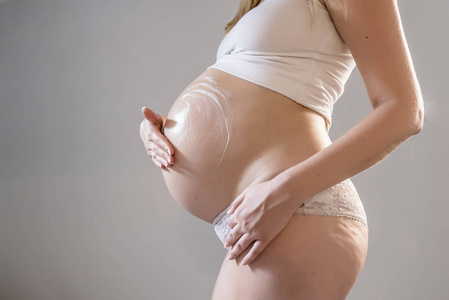孕妇把奶油放在她的肚子上