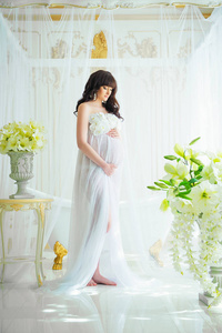 温柔的母亲的期望。怀孕在淡白色裙子的兰花的美丽