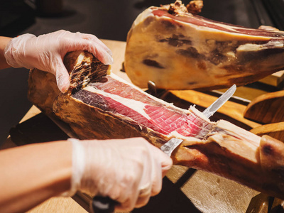 一个女人的手在市场或商店的手套削减了传统的西班牙 jamon de bellota。肉类关闭