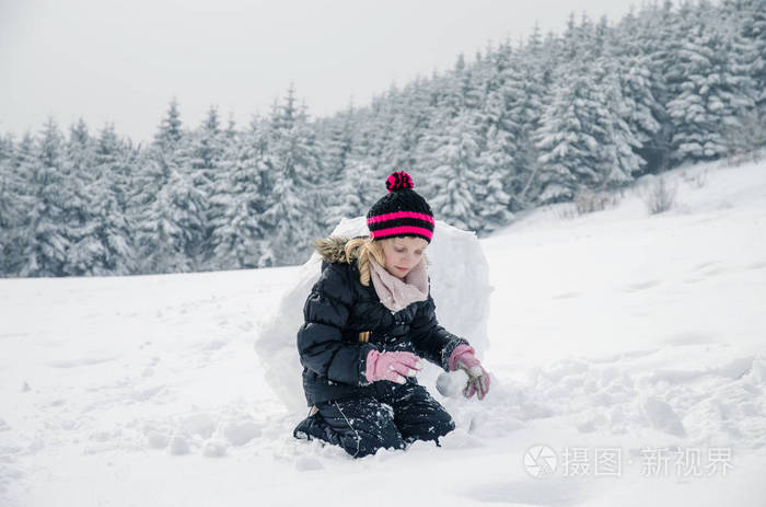 小女孩在森林里堆雪人