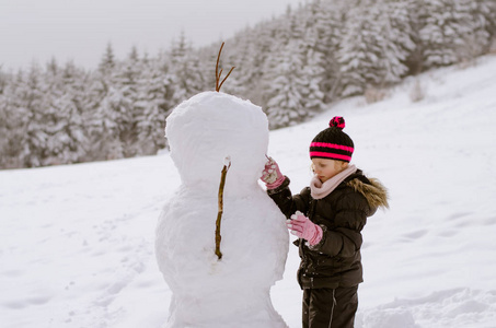 小女孩在森林里堆雪人