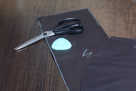 缝纫产品的切割。桌子上有一布带有粉笔记号的衣服。只是躺在剪刀和粉笔