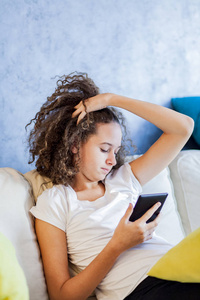 青少年女孩休息和 usiing 数字平板电脑在家里的沙发