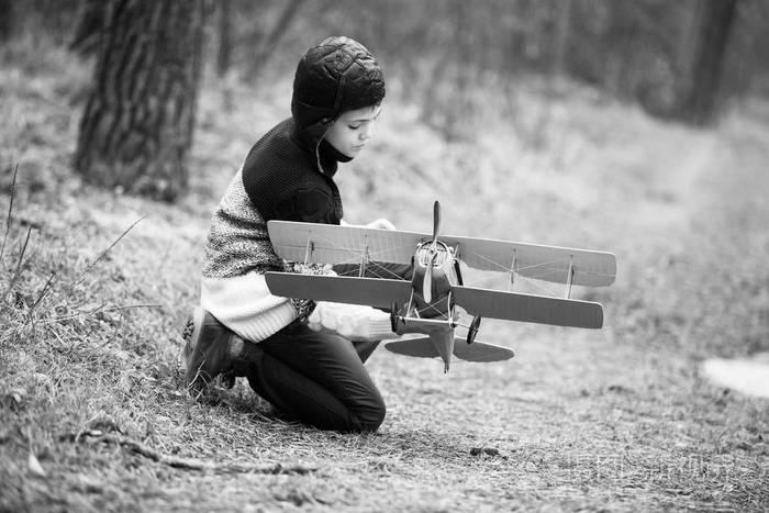 一个男孩在树林里玩玩具飞机。秋季运动会在 w