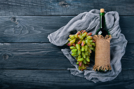 一瓶葡萄酒和葡萄。在木制背景上。顶部视图。文本的可用空间