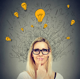 快乐周到的女人抬头看着许多想法头顶上的灯泡照片