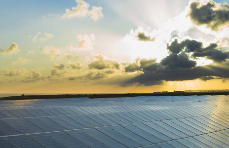 太阳帆板在日出与戏剧性多云天空在诺曼底, 法国。现代电力生产技术。环保型电力生产