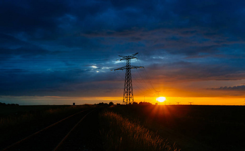 日落时的高压电力线和输电塔。在黄昏中, 波兰人和电线的轮廓。发电和配电。电力工业与自然概念