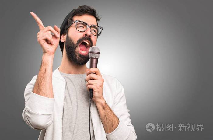 灰色背景下的时髦人用麦克风唱歌