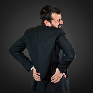 黑色背景的背部疼痛英俊的商人图片