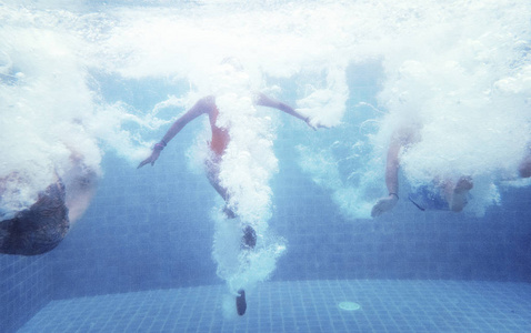 一组人跳入游泳池的水下照片
