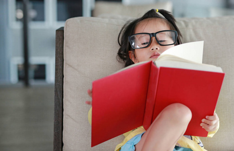 小儿童女孩戴着眼镜读书在库中，教育理念