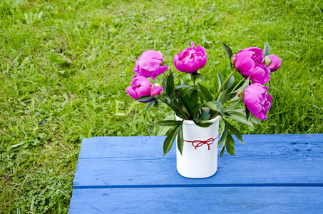 牡丹花在白色花瓶在蓝色庭院桌上