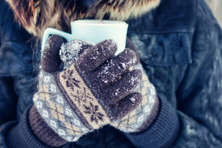 在手套捧着杯茶，白色雪背景的女孩