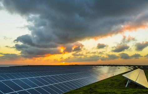 太阳帆板在日出与多云天空在诺曼底, 法国。太阳能现代电力生产技术可再生能源概念。环保型电力生产