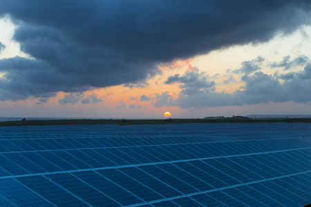 太阳帆板在日出与多云天空在诺曼底, 法国。太阳能现代电力生产技术可再生能源概念。环保型电力生产