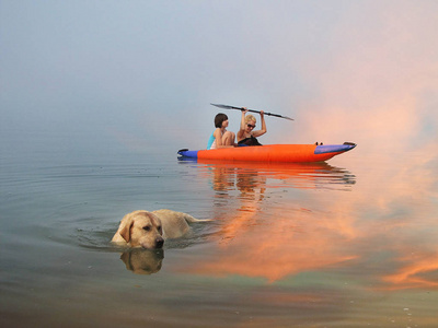 一个有孩子的妇女在充气独木舟皮艇和狗