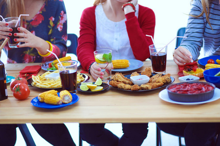 顶视图的一群人在一起时坐在木桌吃饭。在桌子上的食物。人们吃快餐
