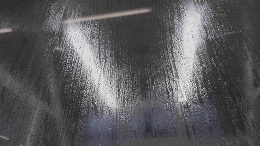 水滴在玻璃上。黑色玻璃背景下的雨滴。雨滴的自然模式。雨在城市。雨滴的作用使窗户上的水汽