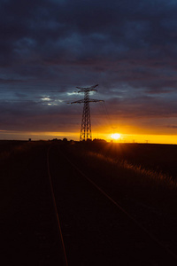 日落时的高压电力线和输电塔。在黄昏中, 波兰人和电线的轮廓。发电和配电。电力工业与自然概念