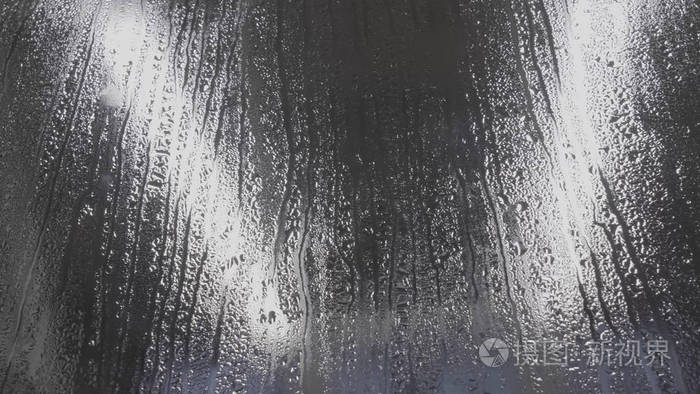 水滴在玻璃上黑色玻璃背景下的雨滴雨滴的自然模式雨在城市雨滴的作用