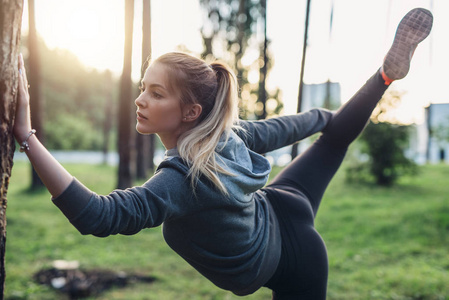 女运动员做腿撑体式伸展运动在城市公园一条腿站立照片