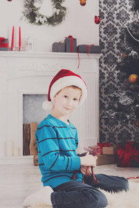 可爱快乐的男孩，在圣诞老人的帽子与玩具圣诞礼物