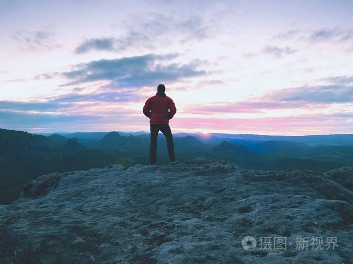 在陡峭的悬崖上的红色夹克的男人的身影.山内早秋天破晓
