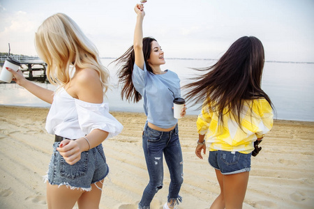 度假。海滩派对。群上夏天日落在海滩上跳舞的快乐年轻妇女