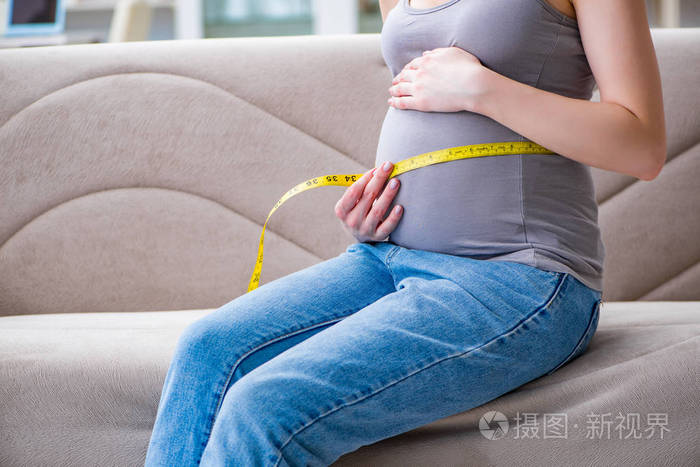 孕妇的肚子肚子坐在家里的沙发上