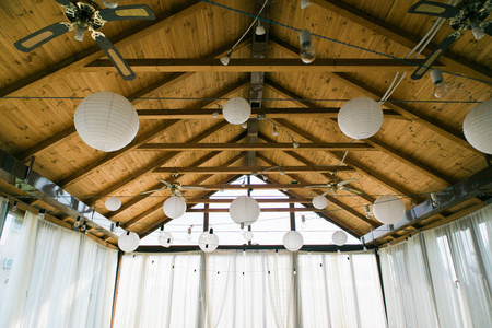 装饰帐篷与灯泡花环。婚礼设置白色纸灯笼在大厦里面, 在木屋顶装饰之下