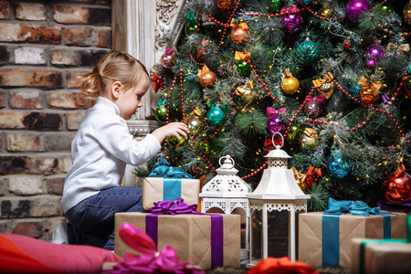 快乐的小女孩在节日装饰圣诞树玩具