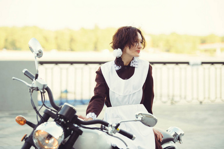 美丽的年轻女子 发型和弓户外与摩托车 身着苏联校服的快乐和健康 女骑车的趣味概念照片 正版商用图片0zw4pr 摄图新视界