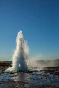 冰岛 Strokkur 喷泉的喷发。冬天的冷色调, 阳光透过蒸汽照射。冰岛地热区