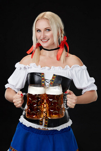 年轻的女人穿裙与黑色背景上的两个啤酒杯子。