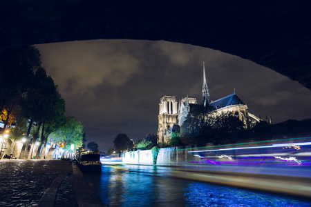 晚上的时候, 巴黎圣母院。著名的古代天主教大教堂在塞纳河码头和城市灯光反射。旅游历史和建筑地标。旅游和旅游理念
