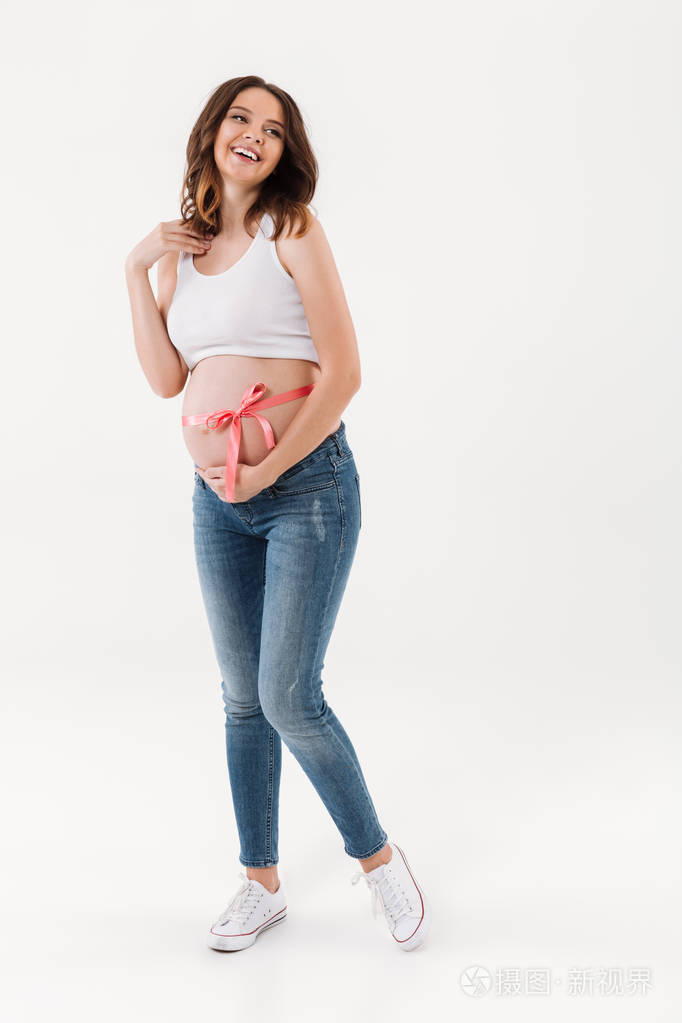 愉快的怀孕的妇女站立的孤立与弓在腹部