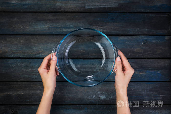 顶部视图妇女手拿着玻璃碗在彩色木背景