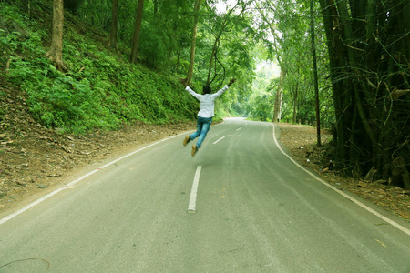 一幅南亚人在森林空旷的公路上跳来跳去的画像