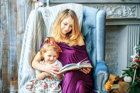 一位年轻的母亲为她的小女儿读一本书。概念的