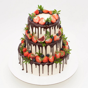 三层的巧克力蛋糕, 用草莓,蓝莓,无花果和绿叶装饰照片