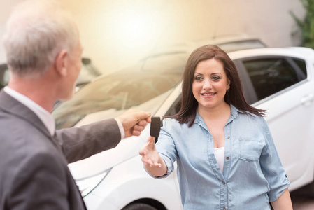 汽车推销员将车钥匙交给年轻的女人，光效果